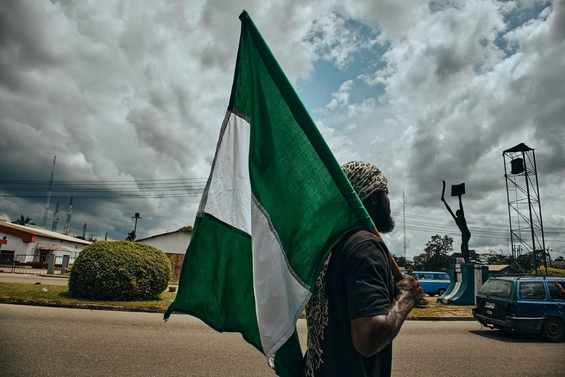 woman in black and white hijab holding green flag